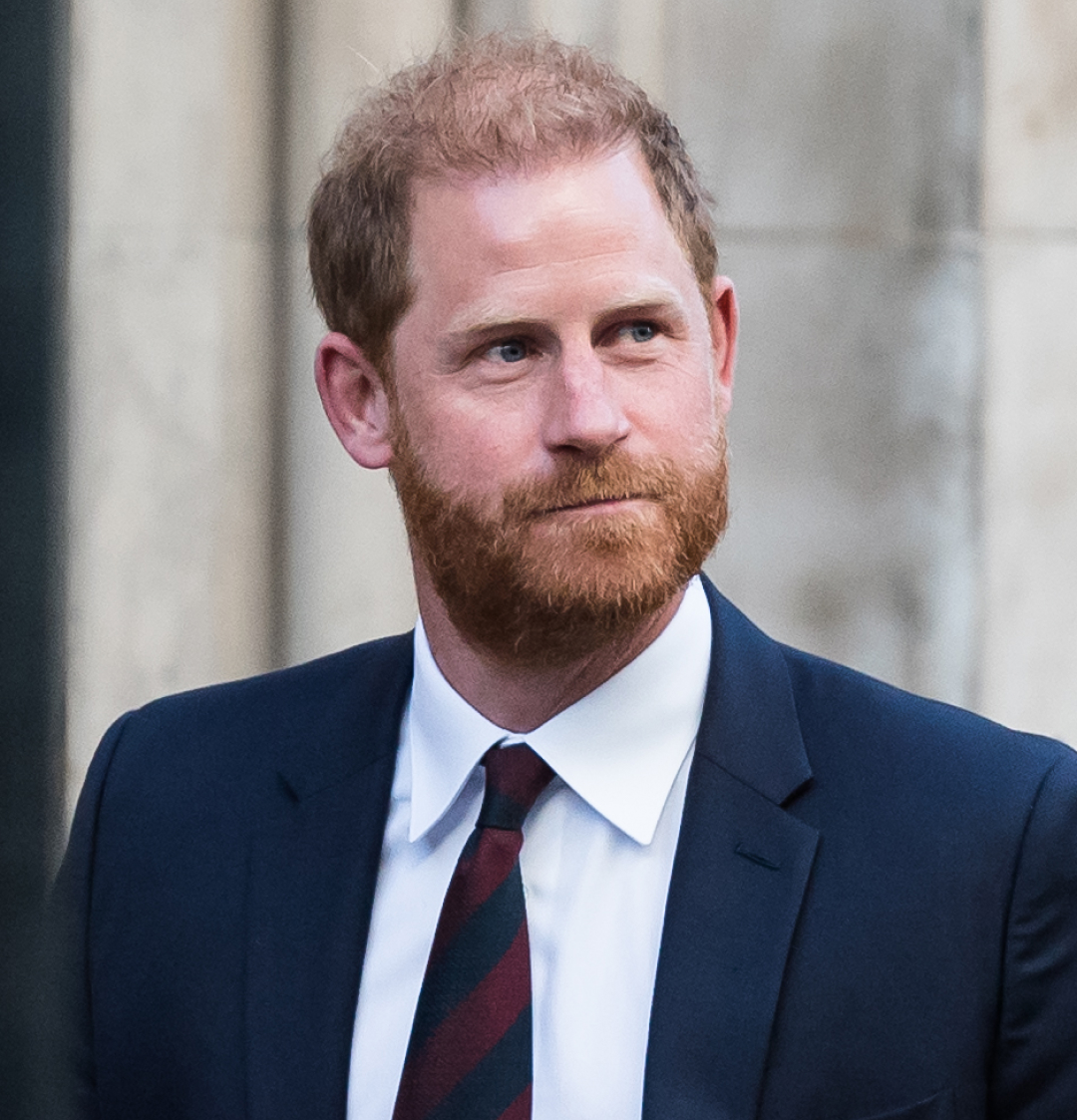 Prince Harry wearing a blue suit and red and blue striped tie 