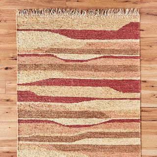 Plain weave terra jute rug on wooden floor.