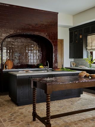 A kitchen with a glossy red tiled hood