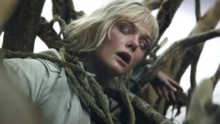 Elle Fanning stands in the middle of a cornfield with Weyland-Yutani branding showing on her eyes in Predator: Badlands.