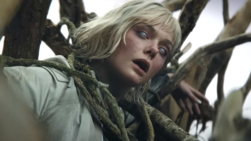 Elle Fanning stands in the middle of a cornfield with Weyland-Yutani branding showing on her eyes in Predator: Badlands. 