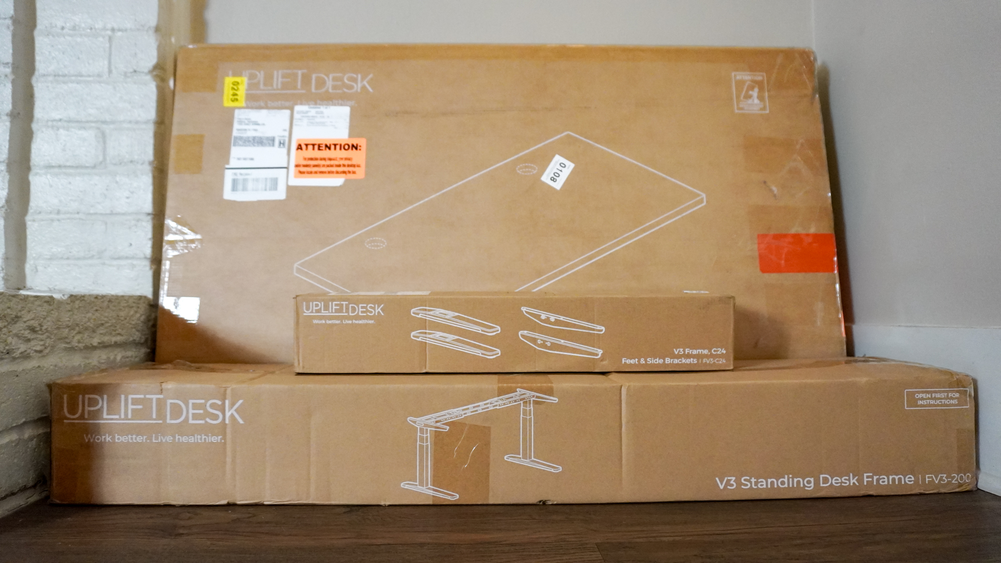 The three boxes the Uplift V3 standing desk arrived to stacked up against a wall