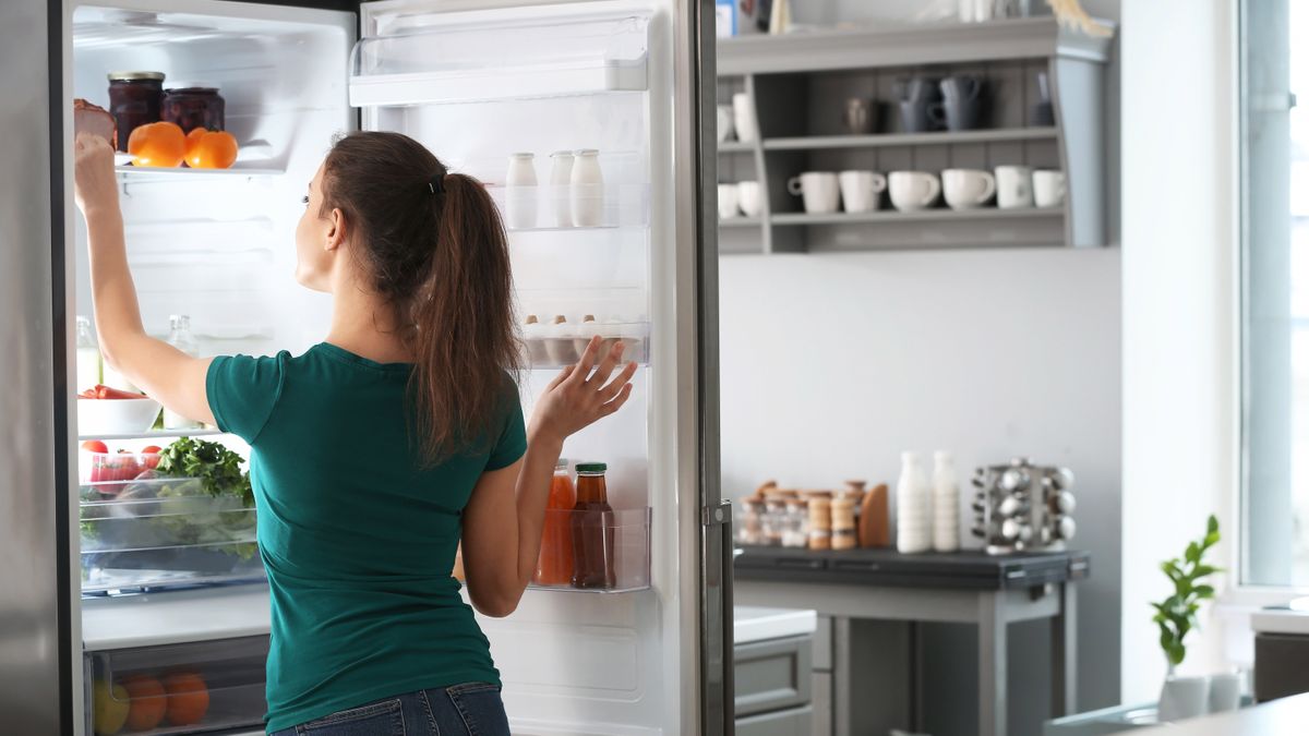 Woman opening a refridgerot door and looking inside