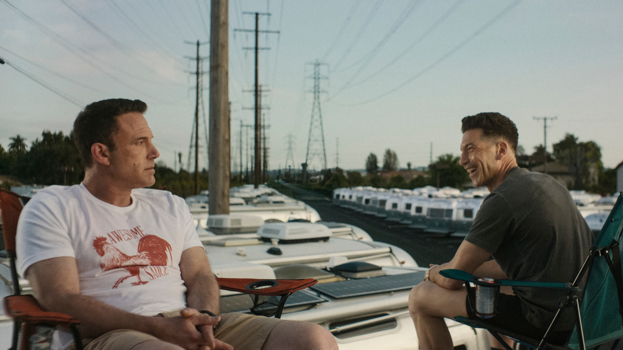 Jon Bernthal laughs in a camping chair while Ben Affleck looks at him with a Stoic face in accountant 2.