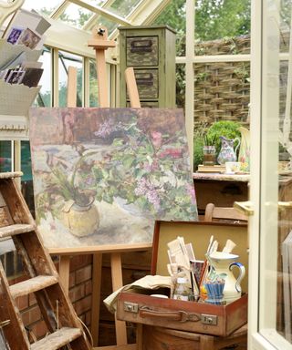 Easels, arts supplies and a canvas painting showing how to add an art station to she shed ideas inside.