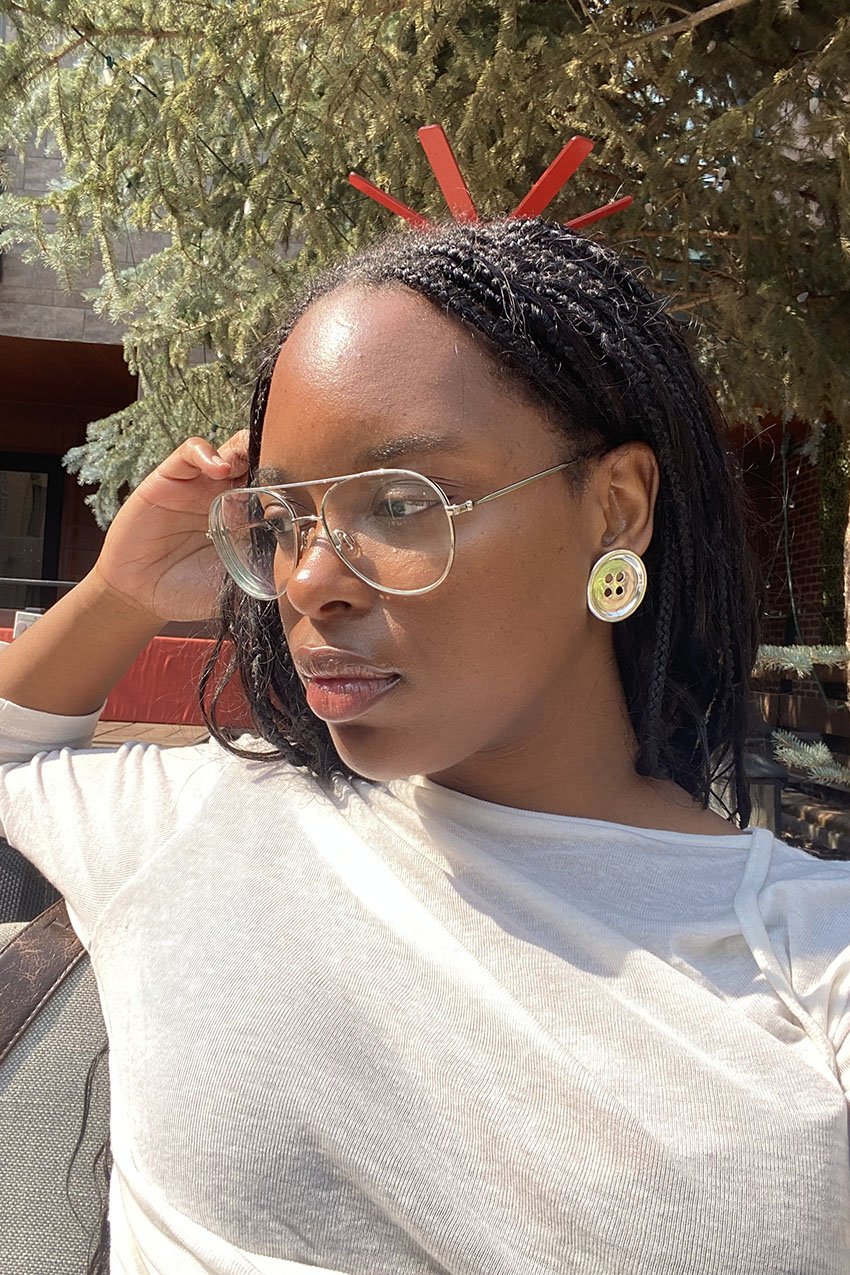 A woman wearing silver button earrings and a white longsleeve top