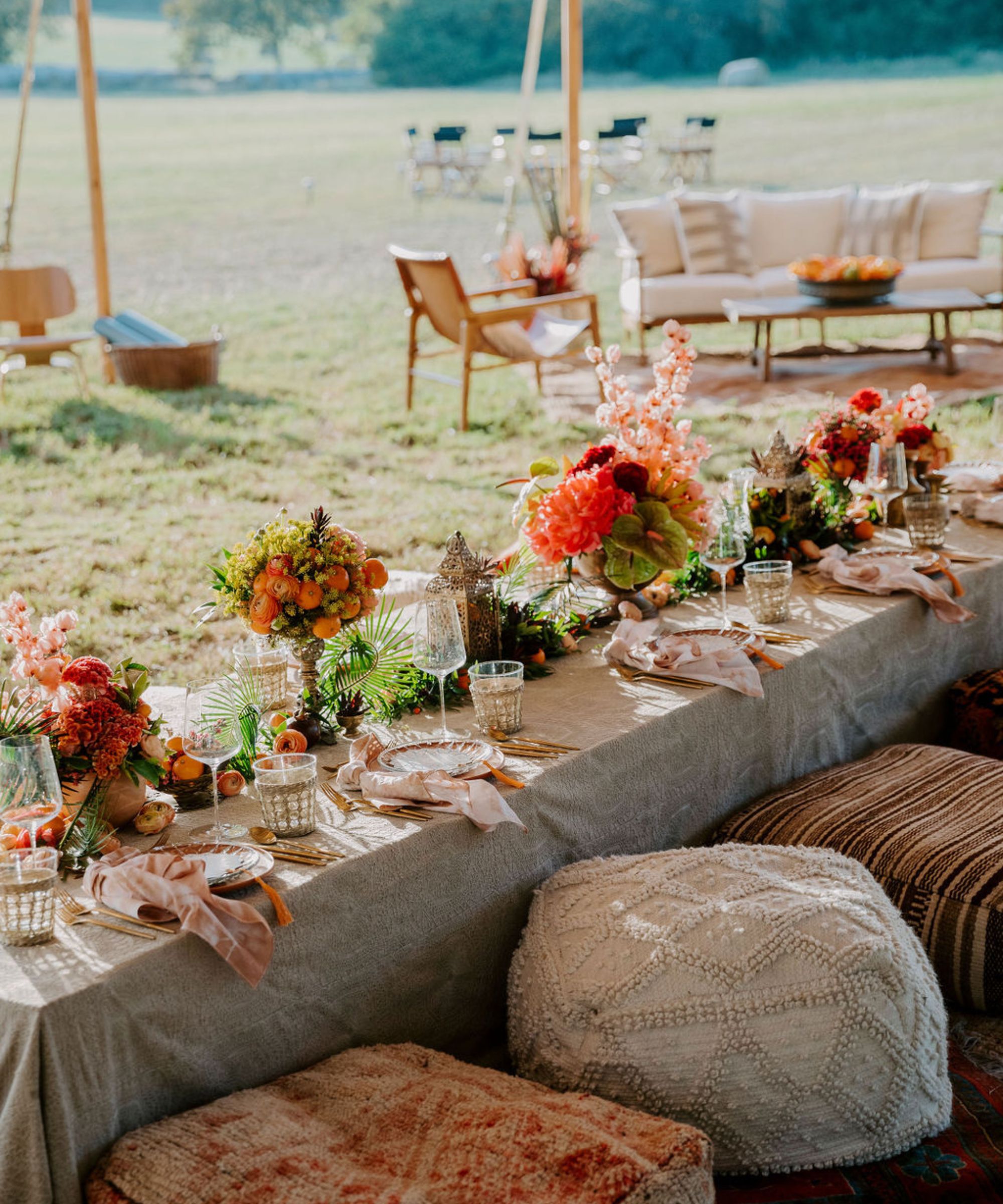 Outdoor low table set up with stools and pink and green flowers with seating area in the background