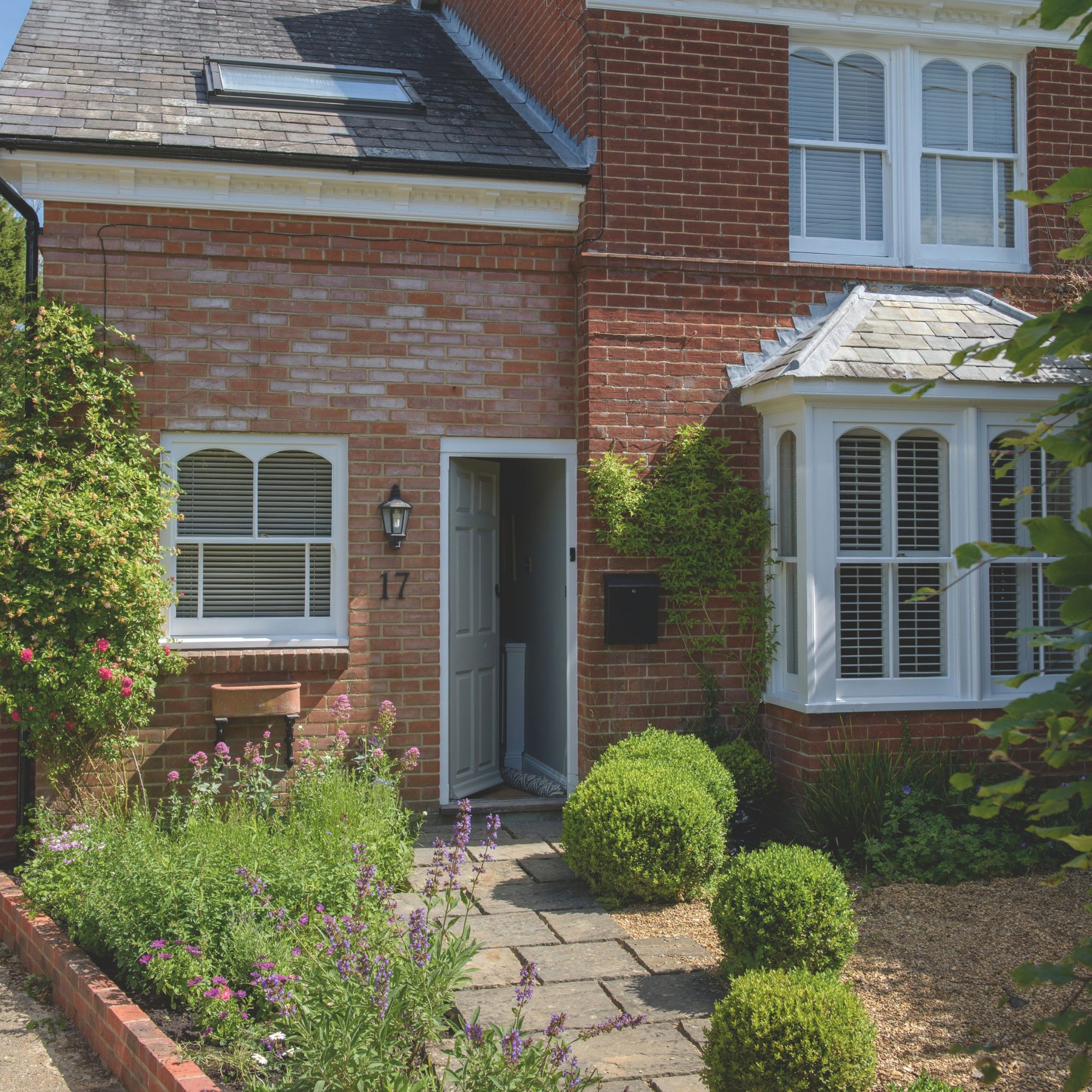 Cottage with front door open and a front garden