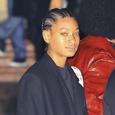 Willow Smith wearing a black coat, black boots, and short sweater dress