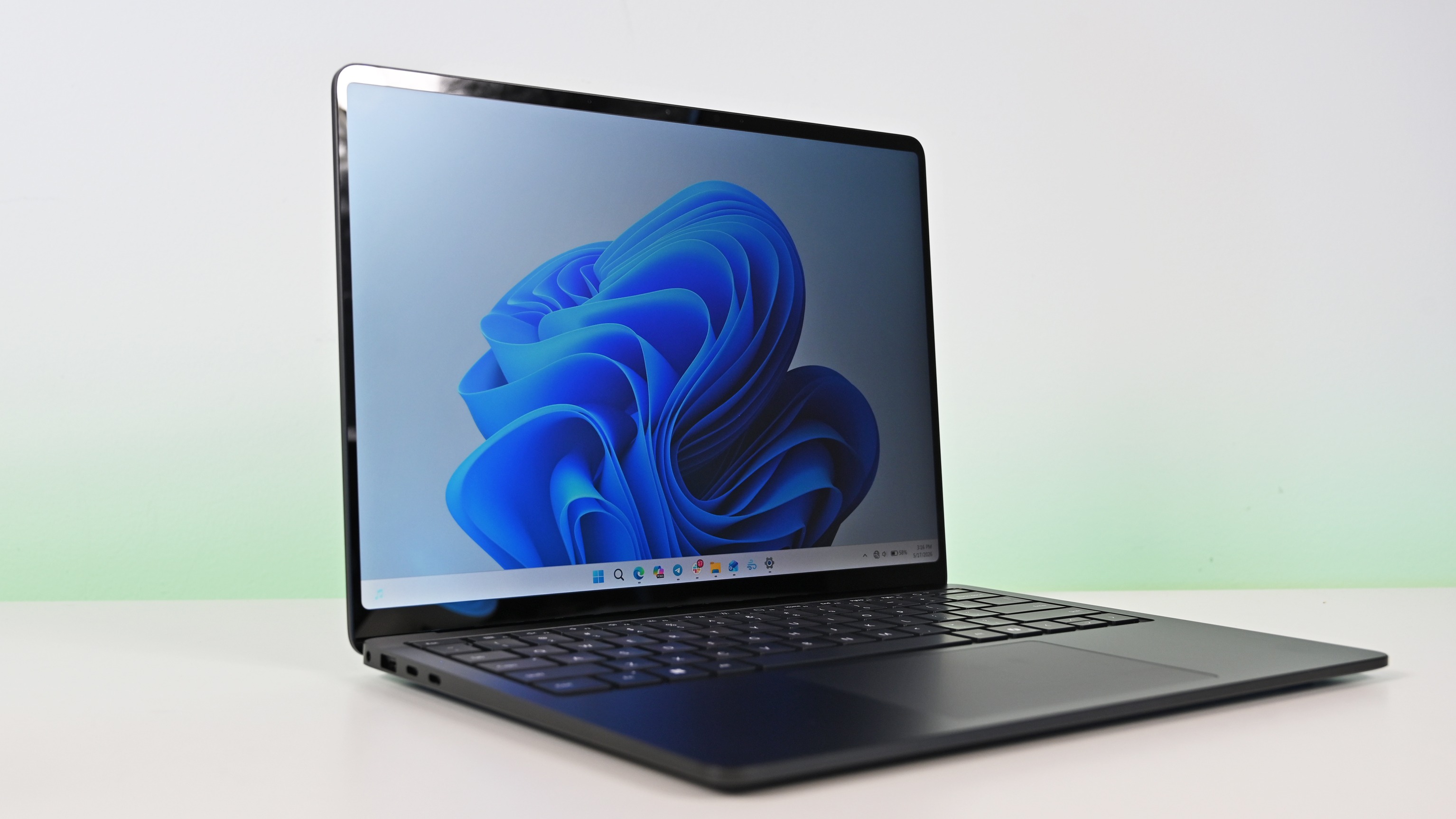 Suface Laptop for Business 8th Edition with a black keyboard and a modern design, displaying a blue abstract swirl on its screen, set against a light gradient background.