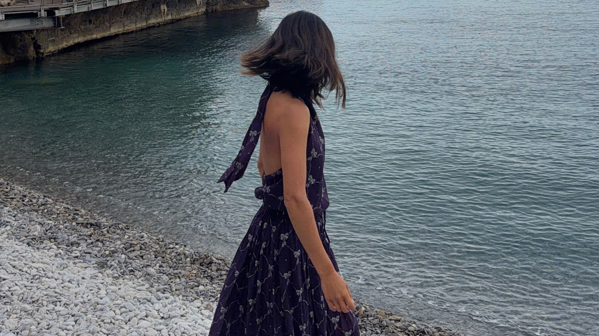 @aimeesong on the beach in a maxi dress and sandals.