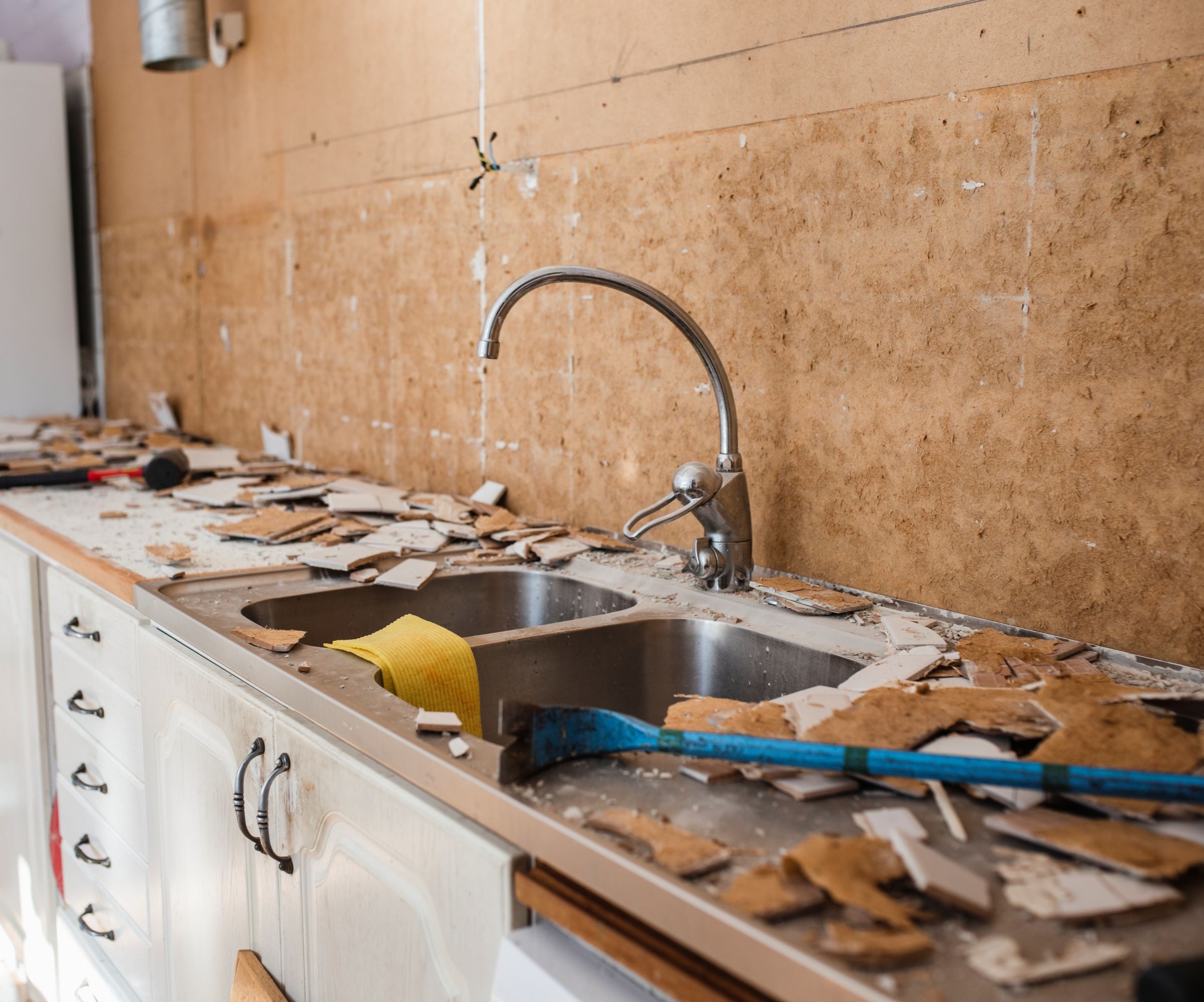 A kitchen renovation with a bare wall with old tiles on the old worktop