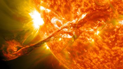 An illustration of a close up on our sun, with the golden ball of orange gas ejecting material to the bottom left of the image. 