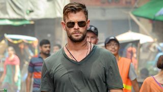 Chris Hemsworth walking down the street wearing sunglasses in Extraction.