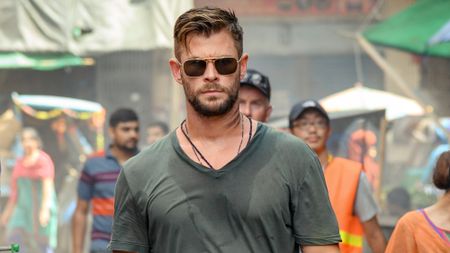 Chris Hemsworth walking down the street wearing sunglasses in Extraction.