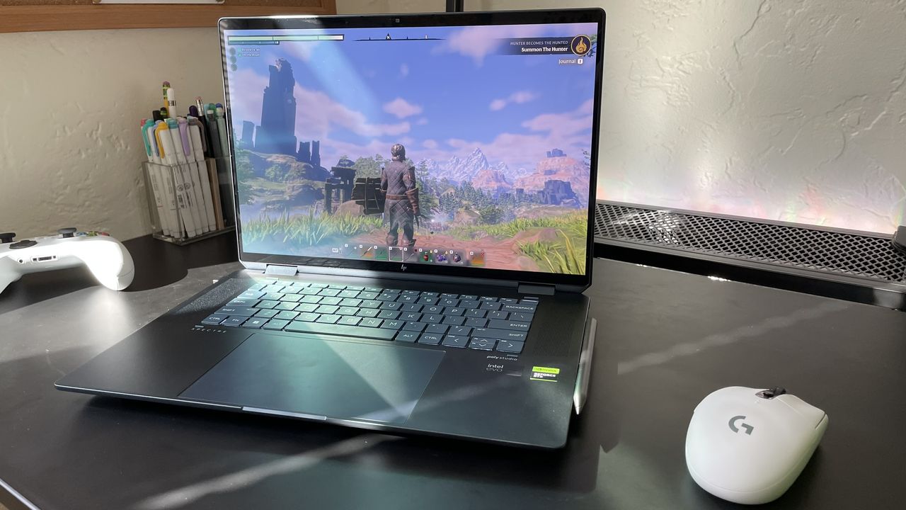 An open and powered on laptop sitting on top of a dark surface against a white background with a white computer mouse to its right.
