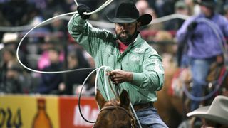 A cowboy swinging a lasso at a rodeo