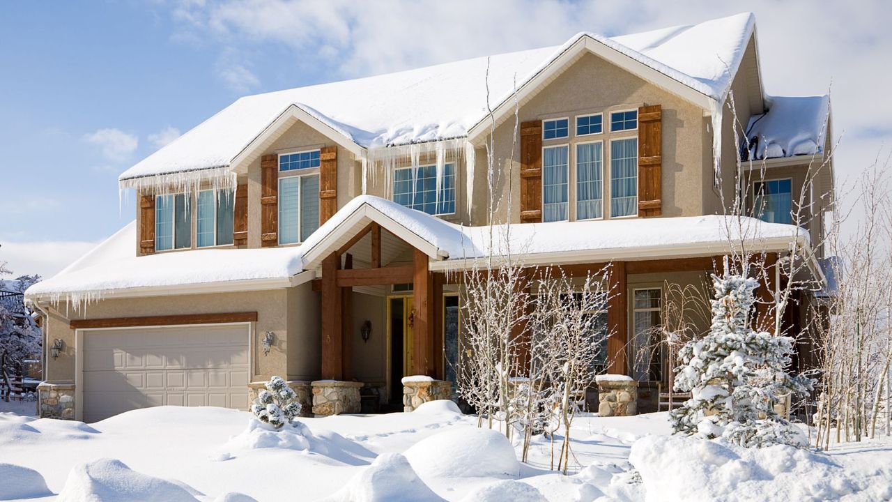 A snow covered luxury home under blue sky.