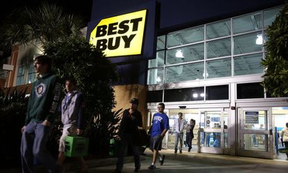 Black Friday shoppers carry discounted items from a Florida Best Buy that opened at 6 p.m. on Thanksgiving Day.