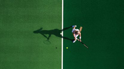 Bird's eye view of woman in whites playing tennis for longevity