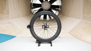 A front Shimano Dura-Ace wheel sits in front of the fan within a wind tunnel