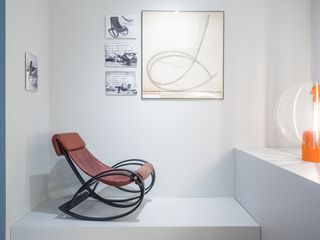 Chair exhibit in a white room, with artwork of the chair design on the walls