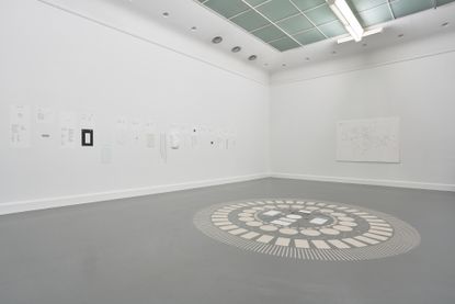 Studio featuring white ceiling, white walls and grey flooring with a circular arrangement of sand based materials on the floor