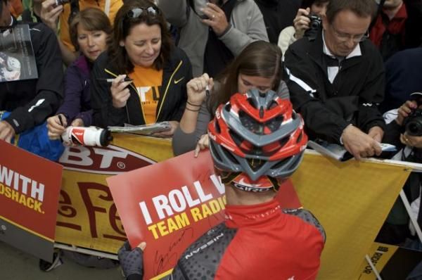 A team RadioShack rider doles out posters to eager fans.