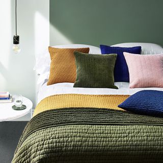 bedroom with coloured cushion and hanging lightbulb