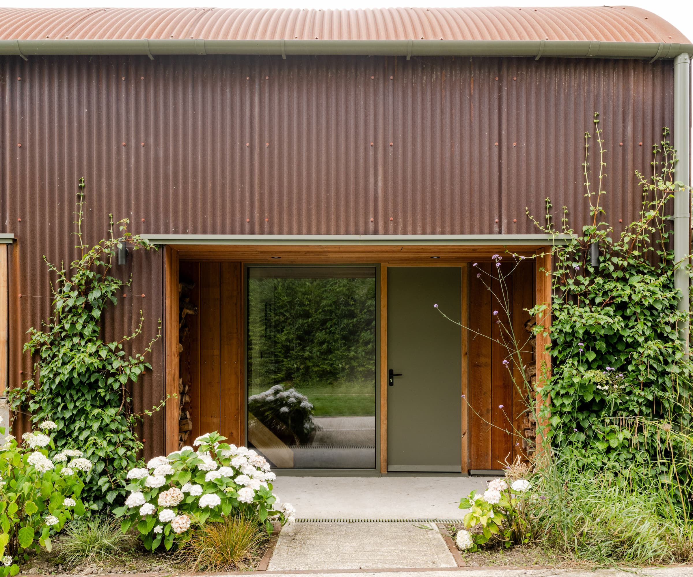 A timber front door with a Corten steel structure