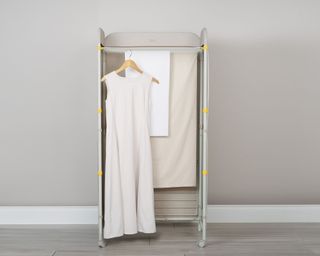 The Eclipse™ 3-tier Ecru Screen Airer with a dress hanging on a hanger