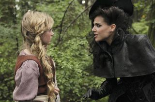 Lana Parrilla in Once Upon a Time as a witch in all black clothing talking to a blonde girl in braids in the woods