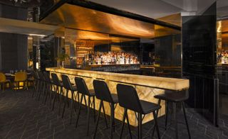 Bar with dark grey bar stools, dark grey floor with geometric design and mirrored surfaces
