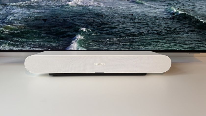 The Sonos Ray soundbar photographed on a white desk in front of a Philips OLED TV