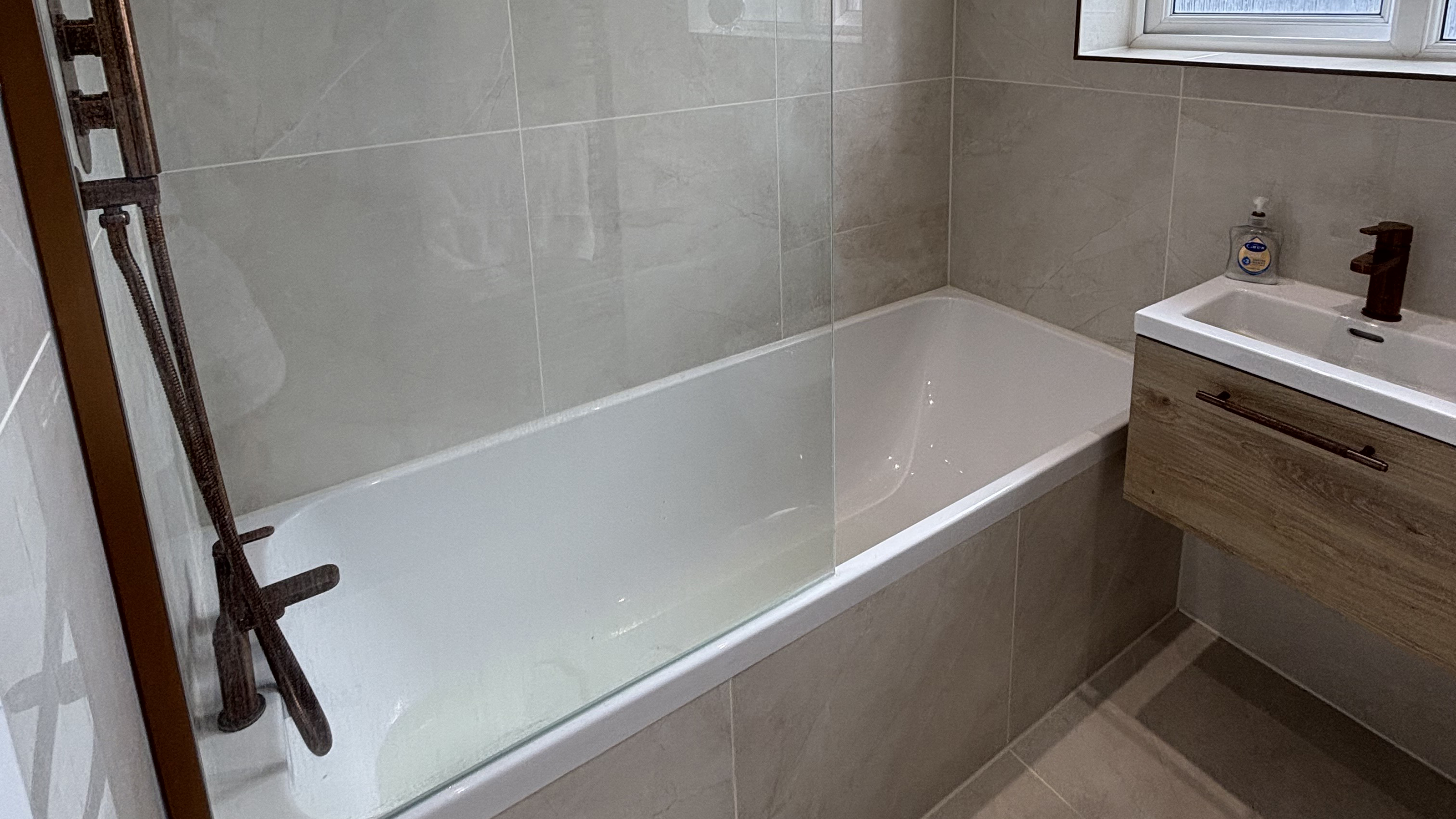 Small bathroom with fitted bath and wall-hung vanity and large-format beige tiles