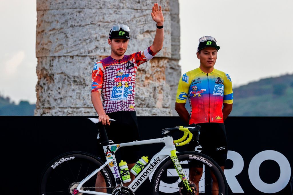 Team Education First rider US Sean Bennett L waves on stage at the Doric Temple of Segesta near Palermo Sicily on October 1 2020 during an opening ceremony of presentation of participating teams and riders two days ahead of the departure of the Giro dItalia 2020 cycling race Photo by Luca Bettini AFP Photo by LUCA BETTINIAFP via Getty Images