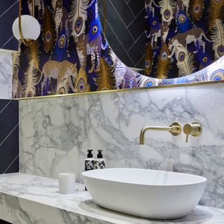 blue and marble cloakroom with cheetah peacock wallpaper, brass taps, blue tiles, marble splashback and counter top
