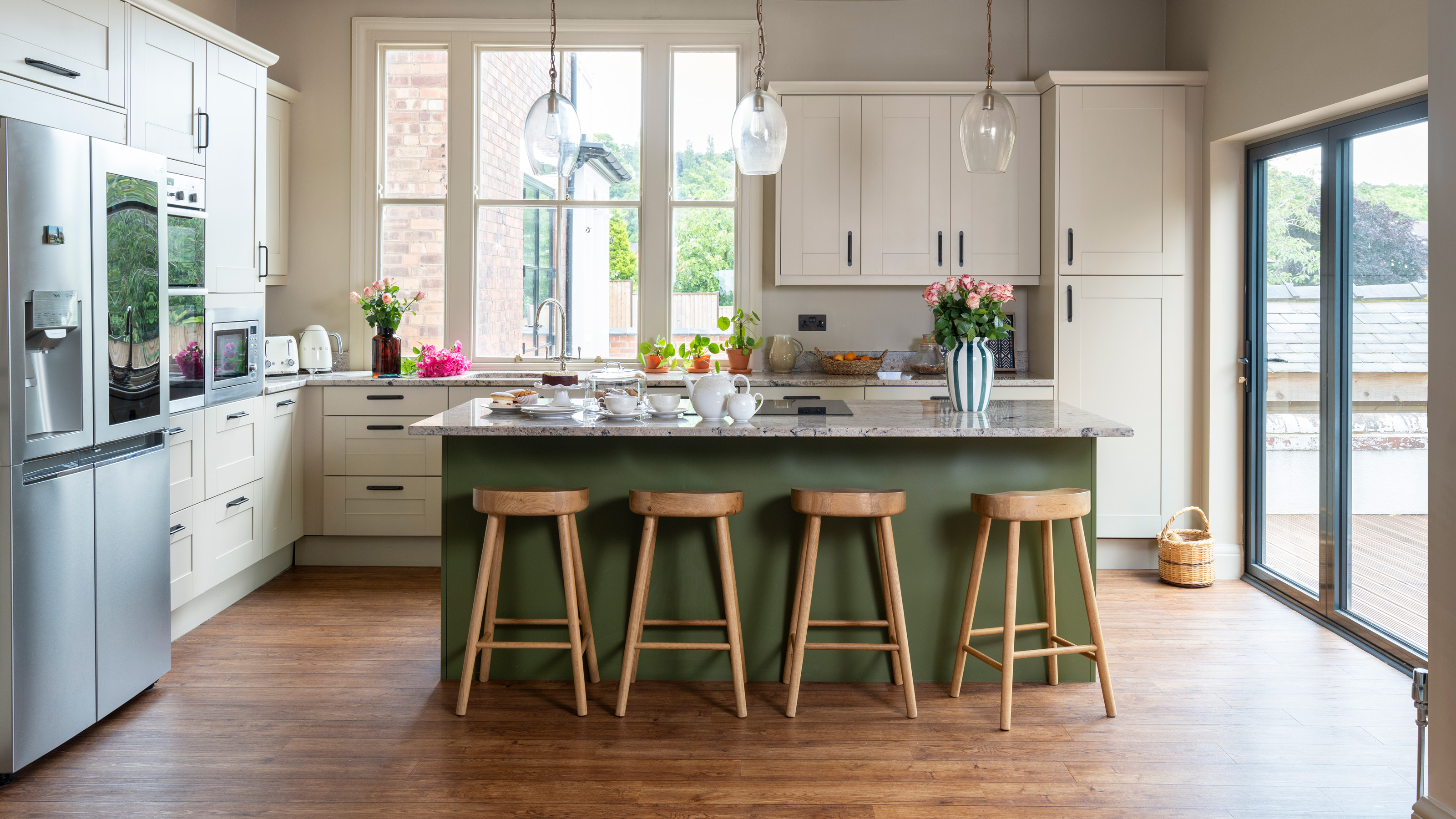 a green and white kitchen with a large kitchen island and a range of kitchen appliances