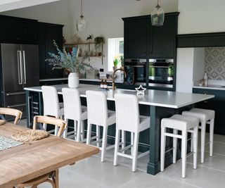 green kitchen with white island and stools