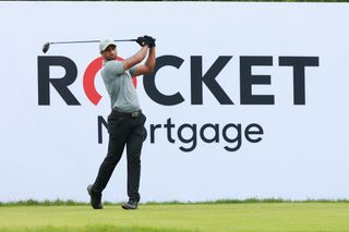 Aaron Rai hits a driver in front of a Rocket Mortgage Classic sign