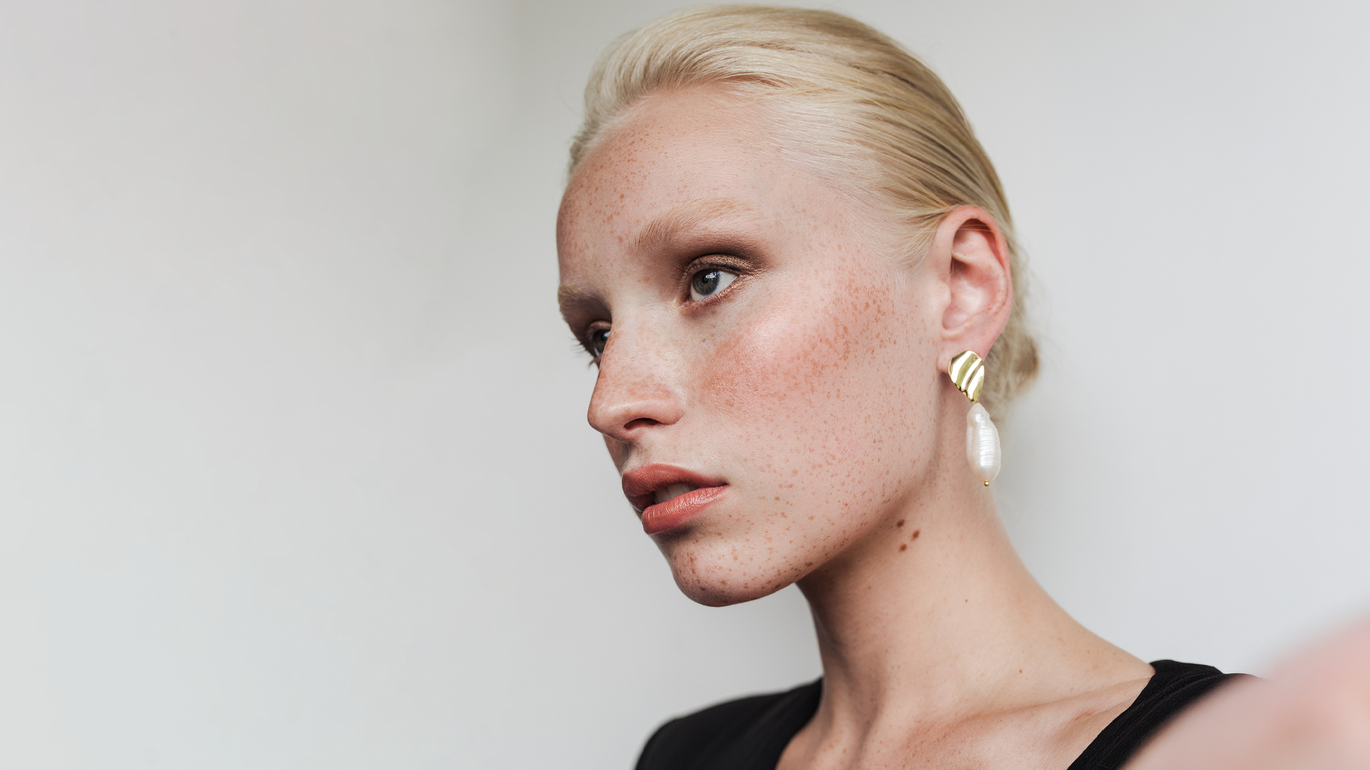 a model with blonde hair tied up looking off to the right hand side