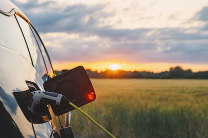 image of an EV charging with a sunset in the background