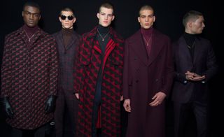 Five men in a line modelling wearing coats with a dark background