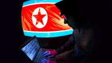 Hacker silhouette working on a laptop with North Korean flag on the background