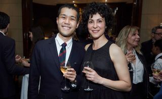 Two guests smiling at camera holding wine glasses