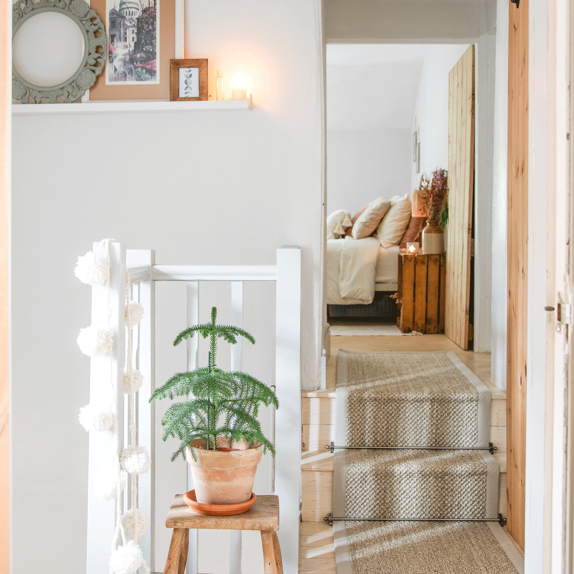 a hallway landing with a small potted Christmas tree with a view into a bedroom