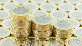 Three piles of pound coins surrounded by another layer of pound coins