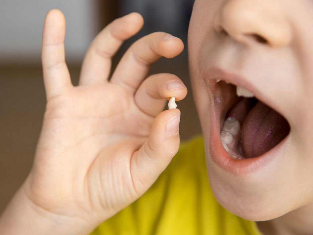 child holding up a lost tooth