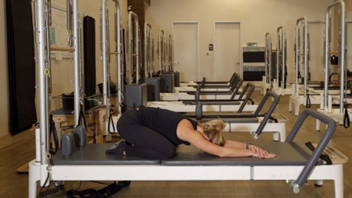 Woman on a Reformer Pilates machine demonstrating an exercise