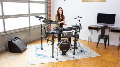 Woman plays a Roland TD-50K2 kit in a room with a wooden floor